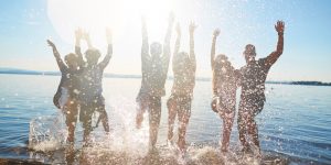 Carefree guys and girls dancing in water at beach party