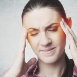 Sad frowning woman with headache touching her temples